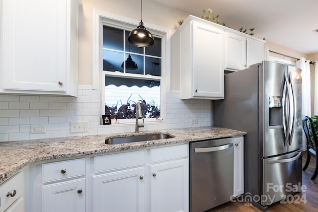 kitchen with backsplash, stainless steel appliances, sink, white cabinetry, and hanging light fixtures