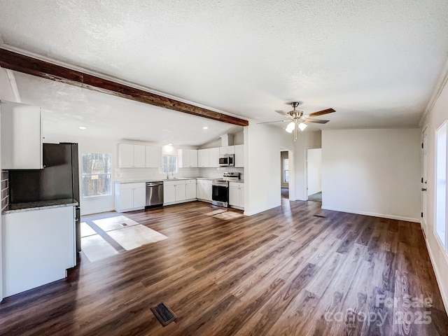 unfurnished living room with dark wood-type flooring, lofted ceiling with beams, sink, ceiling fan, and a textured ceiling