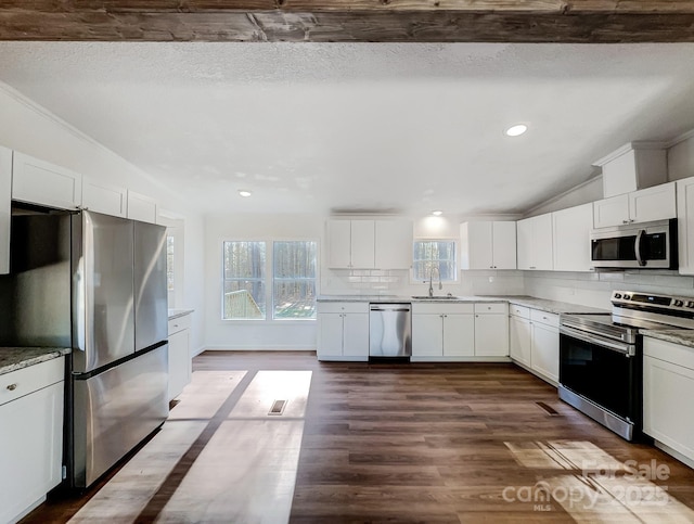 kitchen with dark hardwood / wood-style flooring, stainless steel appliances, white cabinetry, and sink