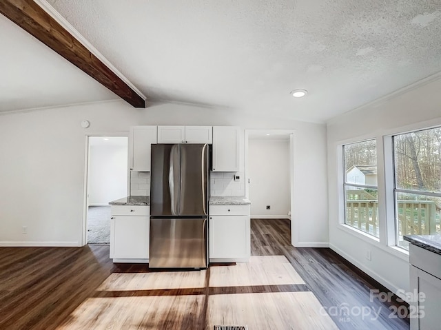 kitchen featuring stainless steel fridge, tasteful backsplash, a textured ceiling, white cabinets, and vaulted ceiling with beams