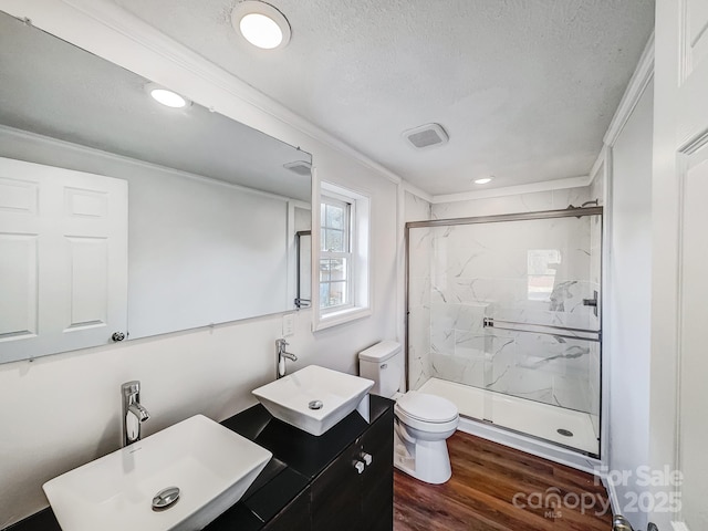 bathroom featuring hardwood / wood-style floors, a shower with door, crown molding, toilet, and a textured ceiling