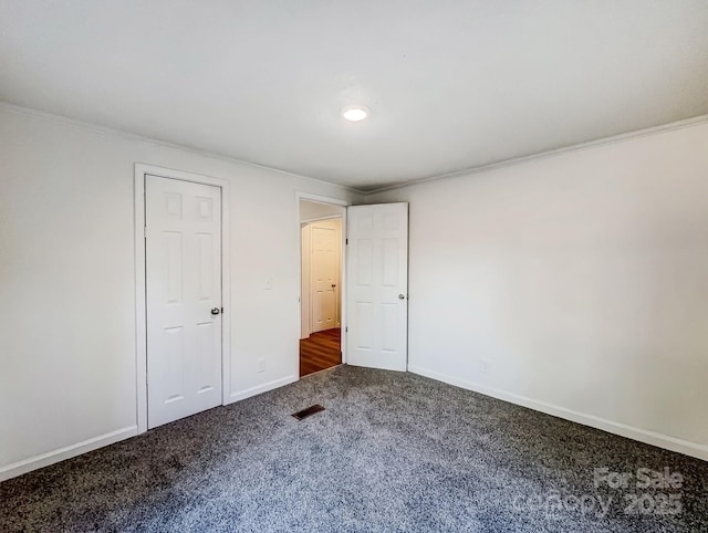 unfurnished bedroom featuring crown molding and dark carpet