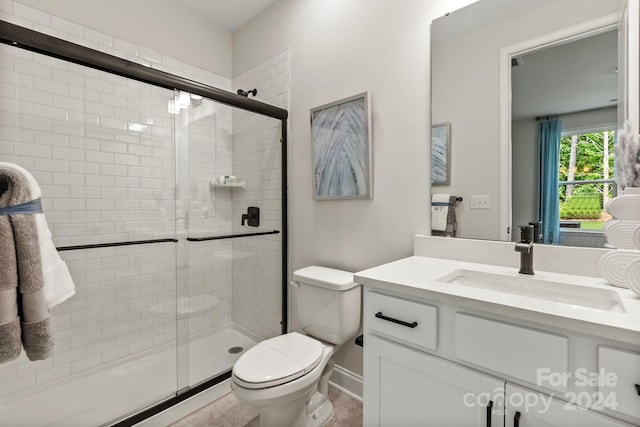 bathroom featuring tile patterned flooring, vanity, an enclosed shower, and toilet