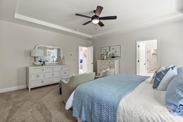 carpeted bedroom with connected bathroom, a raised ceiling, and ceiling fan