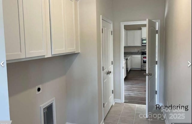 washroom with hookup for an electric dryer, cabinets, and light tile patterned floors