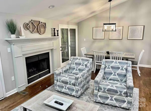 living room featuring wood-type flooring, vaulted ceiling, and an inviting chandelier