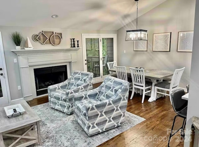 living room with a chandelier, dark wood-type flooring, and vaulted ceiling