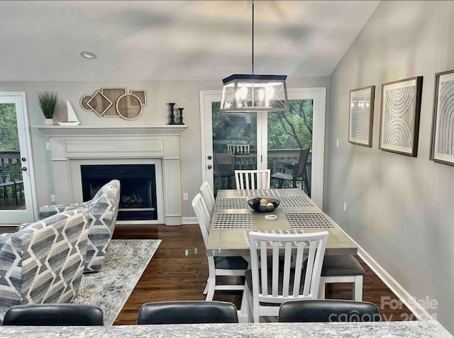 dining area with dark hardwood / wood-style flooring, a chandelier, and vaulted ceiling