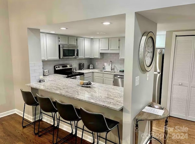 kitchen with sink, a breakfast bar area, light stone counters, kitchen peninsula, and stainless steel appliances