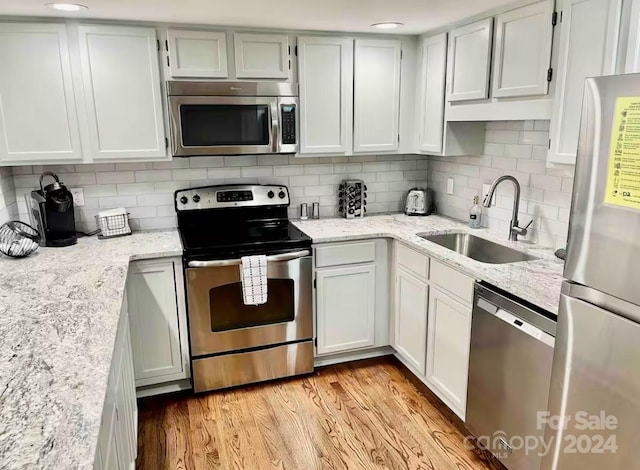 kitchen featuring backsplash, white cabinetry, sink, and stainless steel appliances