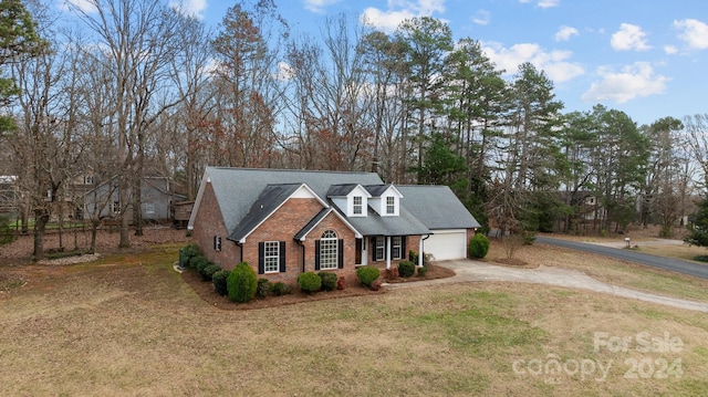 cape cod-style house featuring a garage and a front lawn