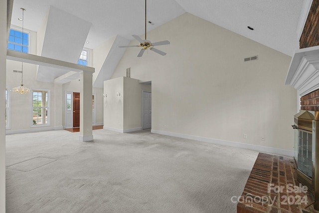 unfurnished living room with carpet, high vaulted ceiling, a healthy amount of sunlight, and ceiling fan with notable chandelier