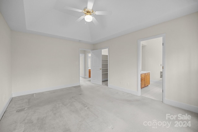 spare room with a raised ceiling, ceiling fan, and light colored carpet