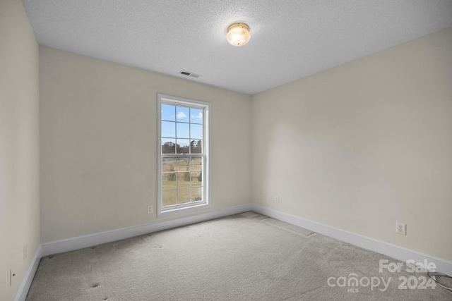 carpeted empty room featuring a textured ceiling