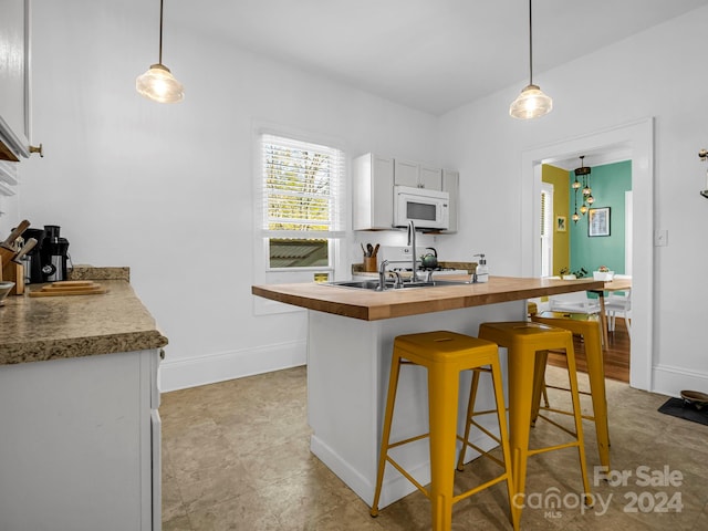 kitchen featuring white cabinets, hanging light fixtures, and a breakfast bar area