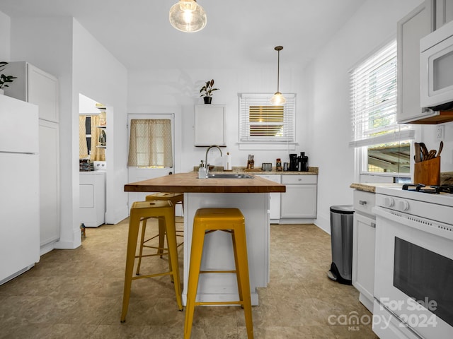 kitchen featuring sink, wood counters, a kitchen breakfast bar, decorative light fixtures, and white appliances