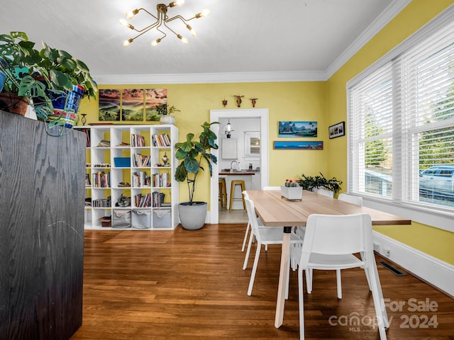 dining area with hardwood / wood-style floors, sink, crown molding, and an inviting chandelier