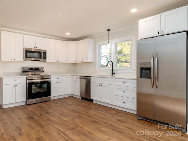 kitchen with sink, stainless steel appliances, dark hardwood / wood-style floors, pendant lighting, and white cabinets