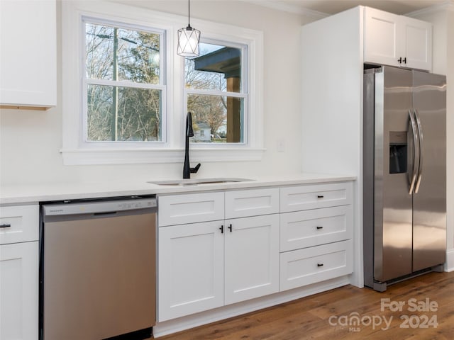 kitchen featuring appliances with stainless steel finishes, sink, pendant lighting, white cabinets, and dark hardwood / wood-style floors