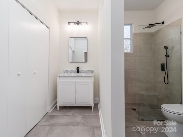 bathroom featuring a tile shower, vanity, and toilet