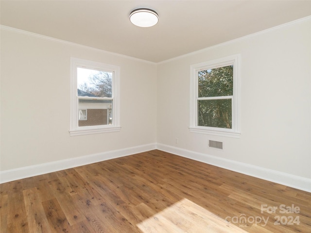 unfurnished room featuring wood-type flooring and ornamental molding