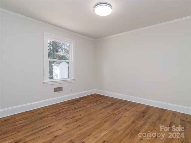 empty room featuring hardwood / wood-style floors and ornamental molding