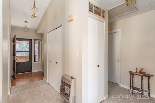 foyer entrance featuring a textured ceiling, carpet flooring, and heating unit