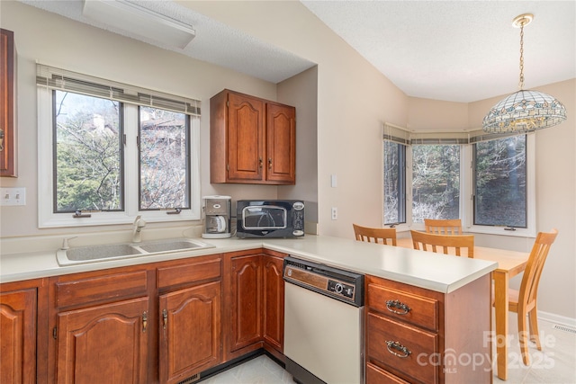 kitchen with kitchen peninsula, dishwasher, hanging light fixtures, sink, and a breakfast bar