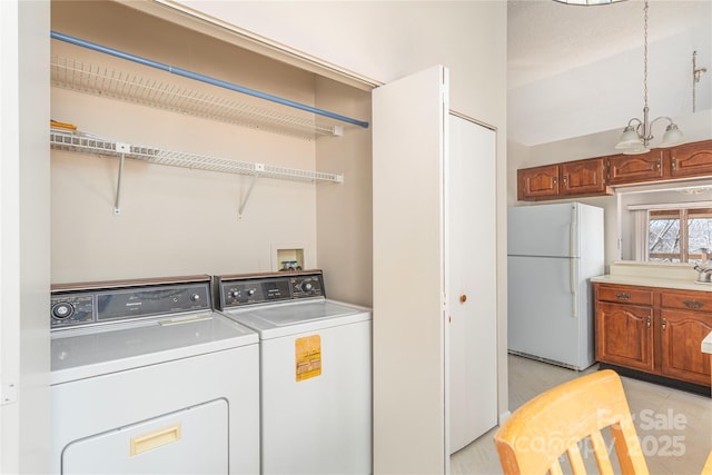 laundry room with light tile patterned flooring, a chandelier, and washer and clothes dryer