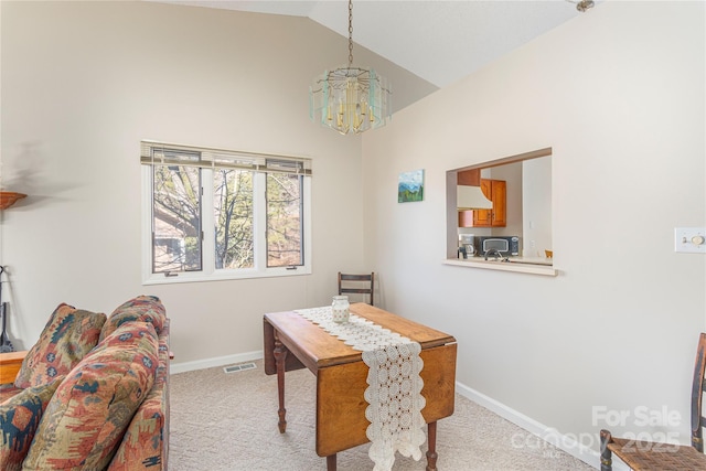 carpeted dining area with a notable chandelier and lofted ceiling