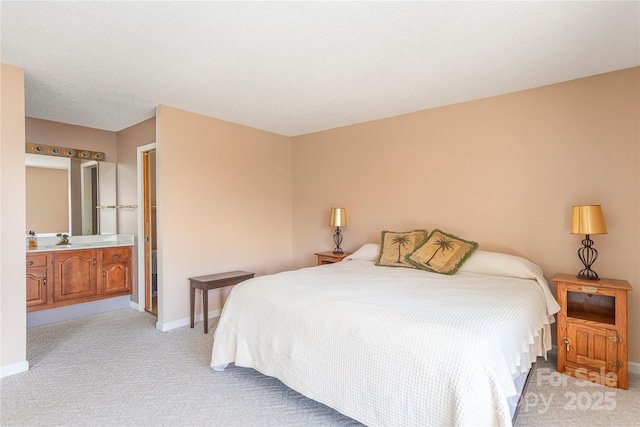 bedroom with ensuite bathroom and light carpet