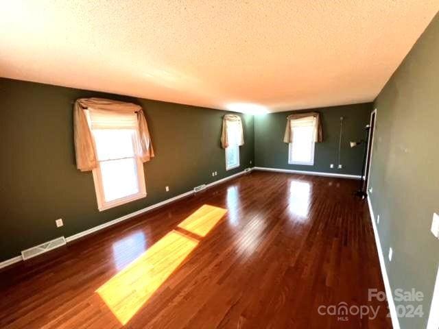 unfurnished room with a textured ceiling and dark wood-type flooring