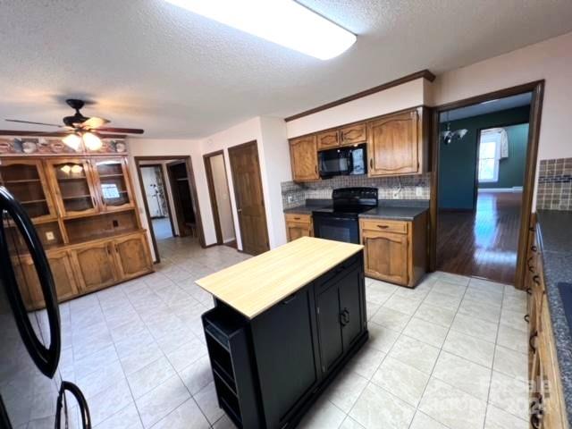 kitchen with black appliances, ceiling fan, a textured ceiling, and tasteful backsplash