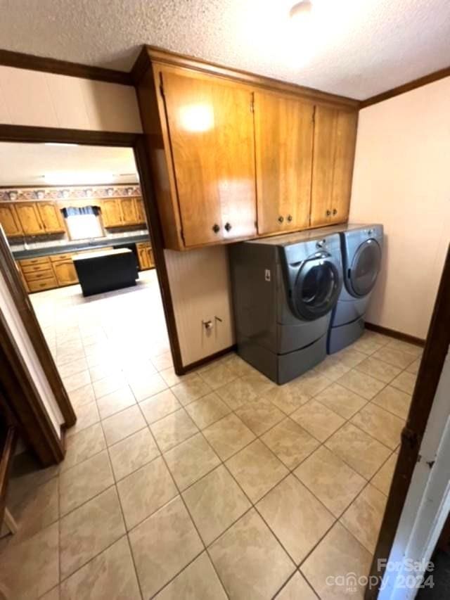 clothes washing area featuring cabinets, independent washer and dryer, a textured ceiling, light tile patterned floors, and ornamental molding