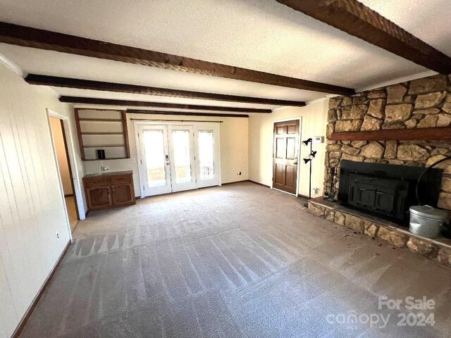 unfurnished living room with beam ceiling, french doors, and carpet