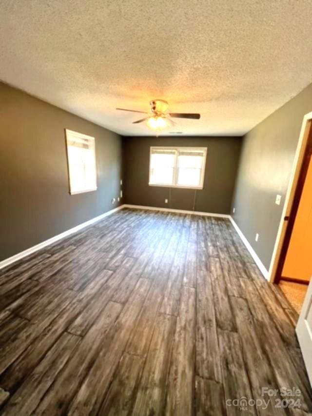 empty room with a textured ceiling, dark hardwood / wood-style floors, and ceiling fan