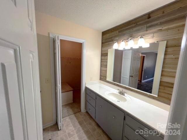 bathroom featuring vanity, a textured ceiling, and wooden walls