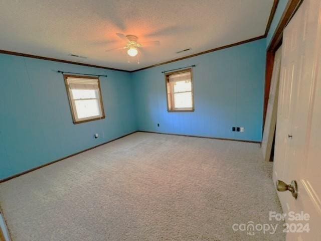 unfurnished bedroom with ceiling fan, crown molding, light colored carpet, and a textured ceiling