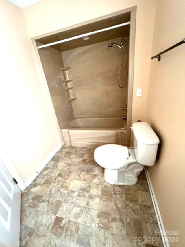 bathroom with tiled shower / bath combo and toilet