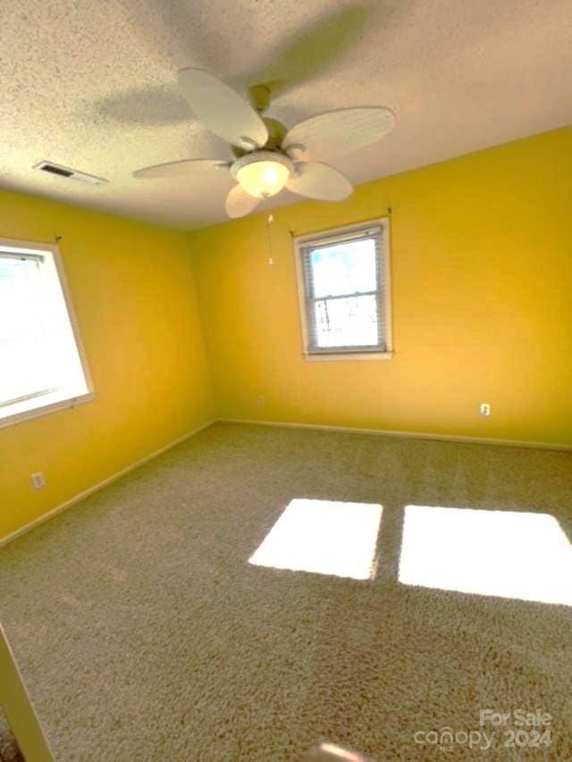 carpeted spare room with ceiling fan and a textured ceiling