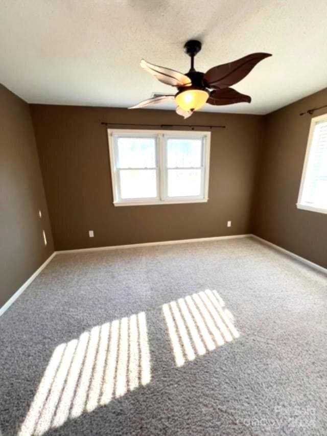 carpeted spare room featuring ceiling fan