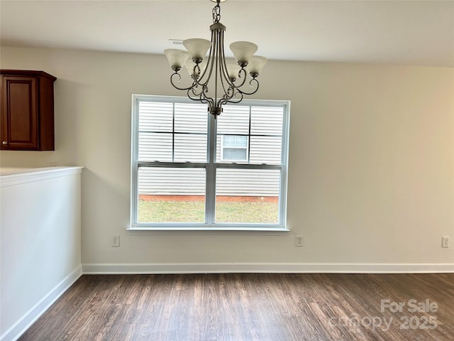 unfurnished dining area with a chandelier and dark hardwood / wood-style flooring