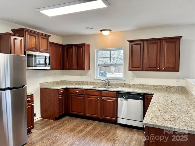 kitchen featuring light stone countertops, appliances with stainless steel finishes, sink, and dark hardwood / wood-style flooring