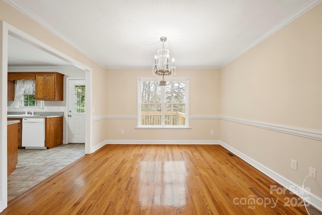 unfurnished dining area featuring crown molding, an inviting chandelier, and light hardwood / wood-style floors