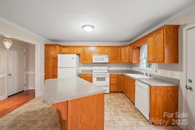 kitchen featuring sink, crown molding, white appliances, a center island, and a textured ceiling