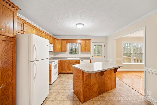 kitchen with white appliances, a healthy amount of sunlight, sink, and a kitchen island