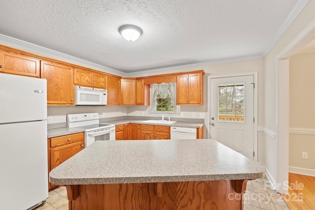 kitchen featuring white appliances, ornamental molding, sink, and a kitchen island