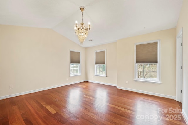 unfurnished room with hardwood / wood-style flooring, a healthy amount of sunlight, a chandelier, and vaulted ceiling