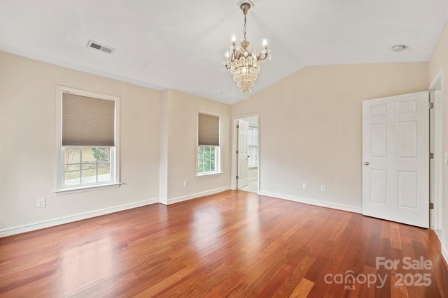 unfurnished room with lofted ceiling, hardwood / wood-style floors, and a chandelier