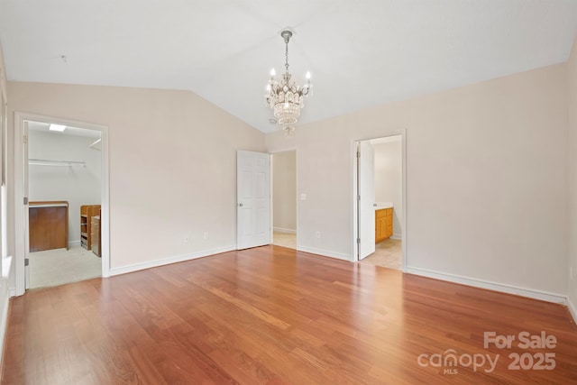 spare room featuring vaulted ceiling, a notable chandelier, and light wood-type flooring